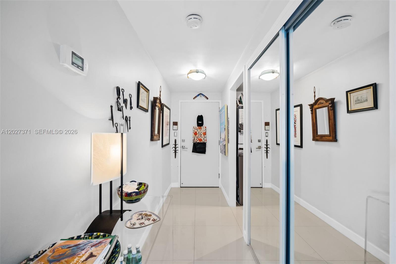 A bright hallway features white walls, tiled flooring, a mirrored closet, and wall-mounted decor — 3301 NE 5th Ave # 209, Miami FL 33137, MIAMI, FL