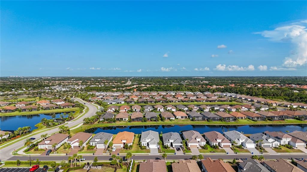 An aerial view shows a suburban neighborhood with houses, a winding road, and a pond — 6145 GRANDVIEW HILL COURT, BRADENTON, FL