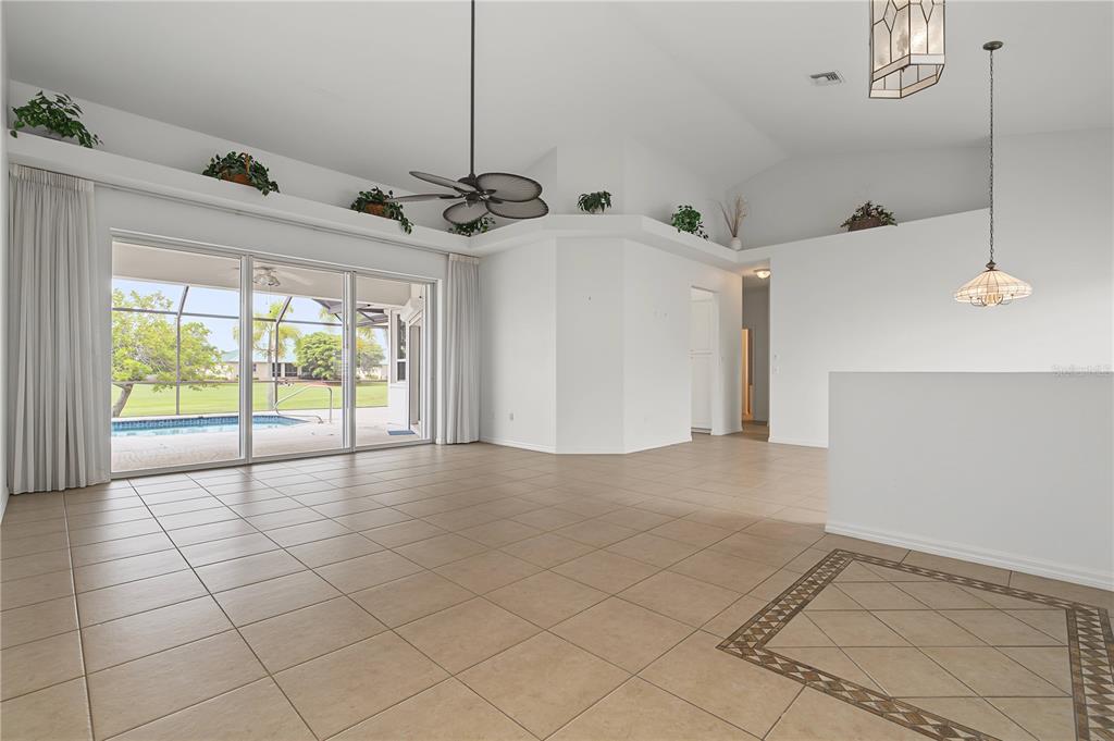 A bright, tiled living room features vaulted ceilings, a ceiling fan, and sliding glass doors — 1612 SUZI STREET, PUNTA GORDA, FL