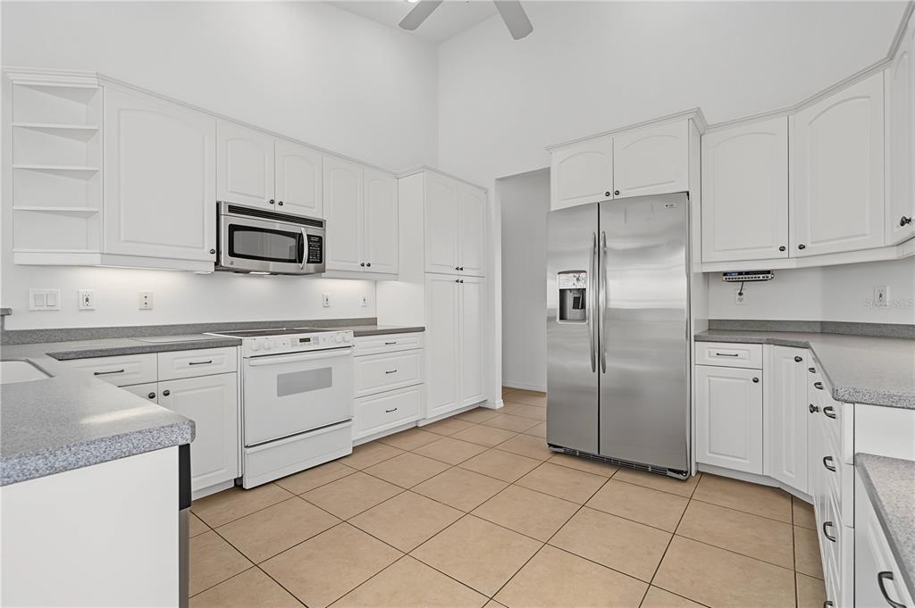 A kitchen featuring white cabinets, stainless steel appliances, gray countertops, and light-colored tile flooring — 1612 SUZI STREET, PUNTA GORDA, FL