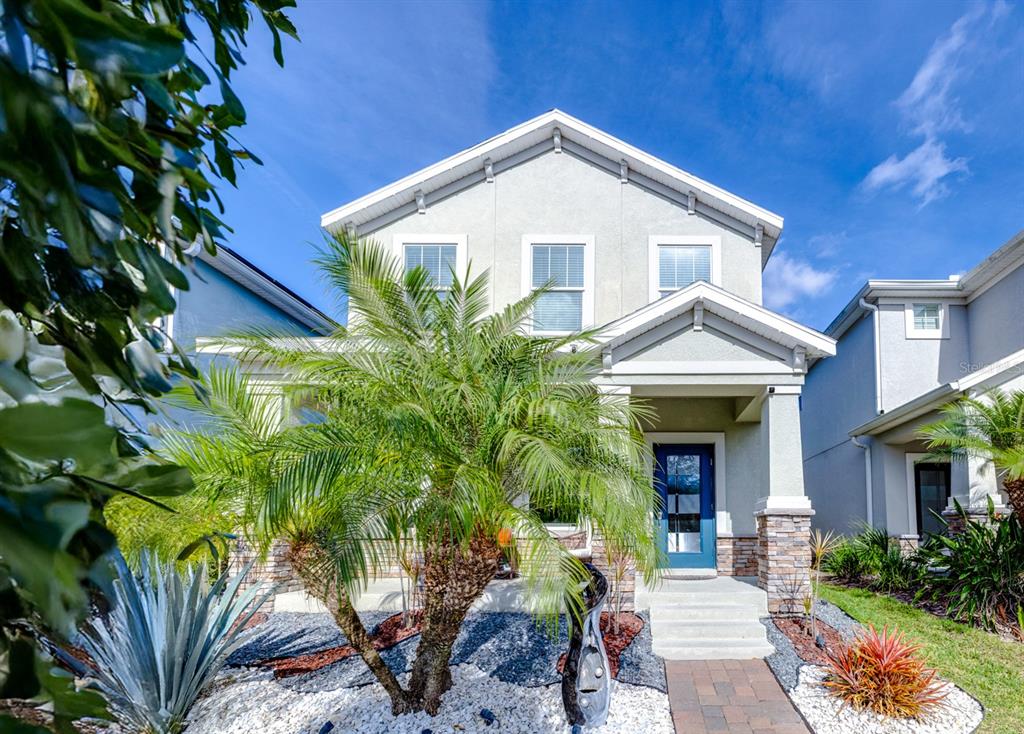A two-story house with a blue front door, stone accents, and a palm tree — 11813 GINSBERG PLACE, ORLANDO, FL