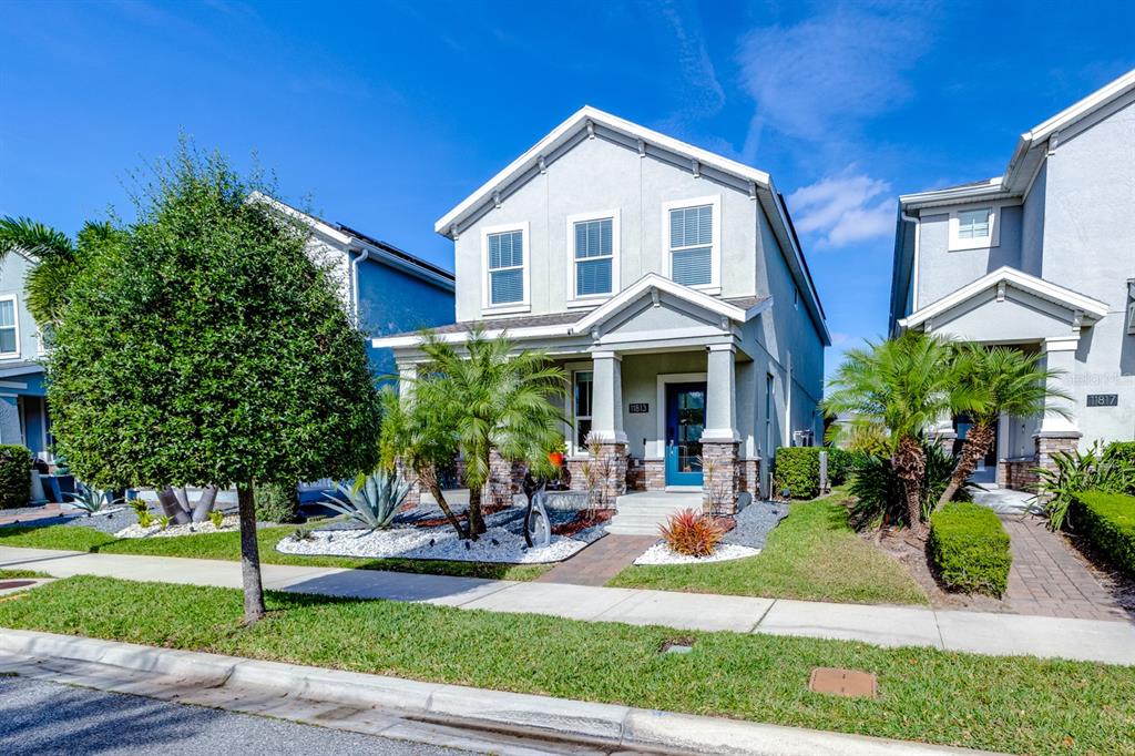 A two-story suburban house with a blue front door and stone-accented porch — 11813 GINSBERG PLACE, ORLANDO, FL