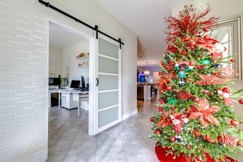 A home office with a sliding barn door sits beside a decorated Christmas tree — 11813 GINSBERG PLACE, ORLANDO, FL