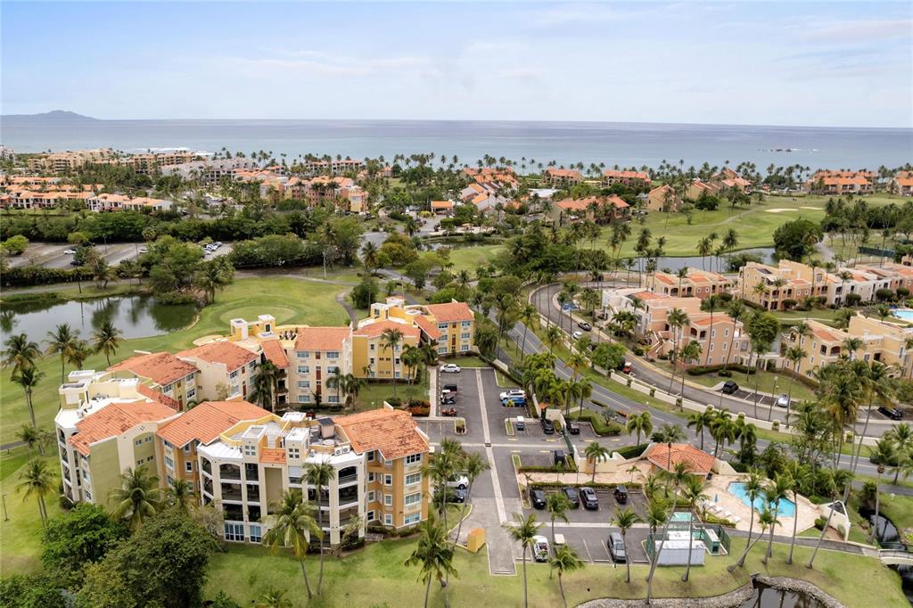 An aerial view shows multi-story residential buildings surrounded by palm trees, a golf course, and ocean — C-3 CANDELERO ROAD UNIT C-3, HUMACAO, PR