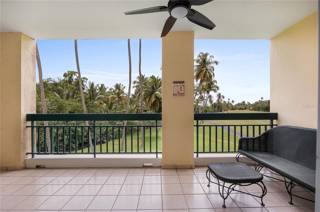 A covered balcony features tiled flooring, a ceiling fan, and a view of palm trees — C-3 CANDELERO ROAD UNIT C-3, HUMACAO, PR