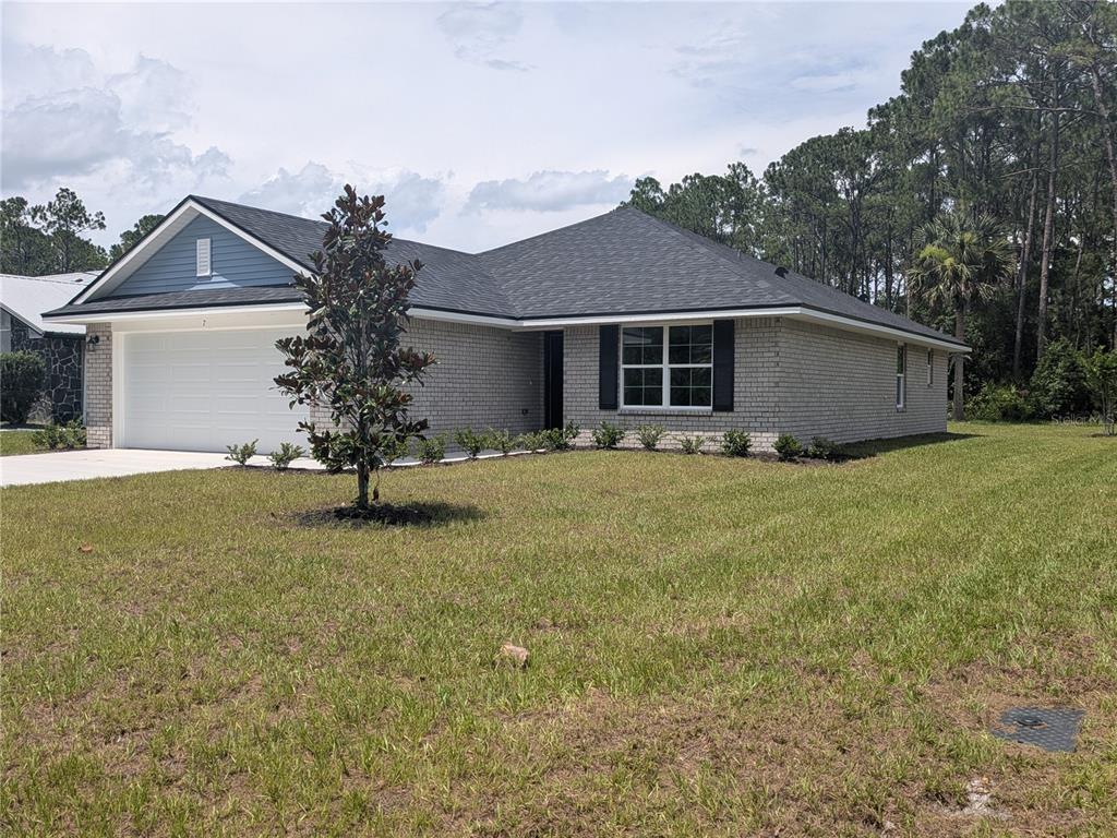 A kitchen with white cabinets, granite countertops, stainless steel appliances, and dark wood flooring — 7 ULLYNN PLACE, PALM COAST, FL