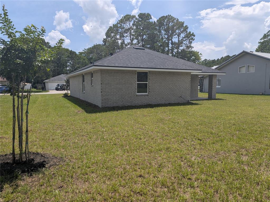 A kitchen with white cabinets, granite countertops, and stainless steel appliances opens to a living area — 7 ULLYNN PLACE, PALM COAST, FL
