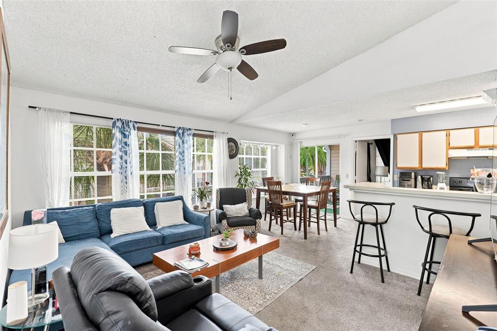 An open-concept living and dining area features a blue sectional sofa, dining table, and kitchen — 1085 S HIAWASSEE ROAD UNIT 523, ORLANDO, FL