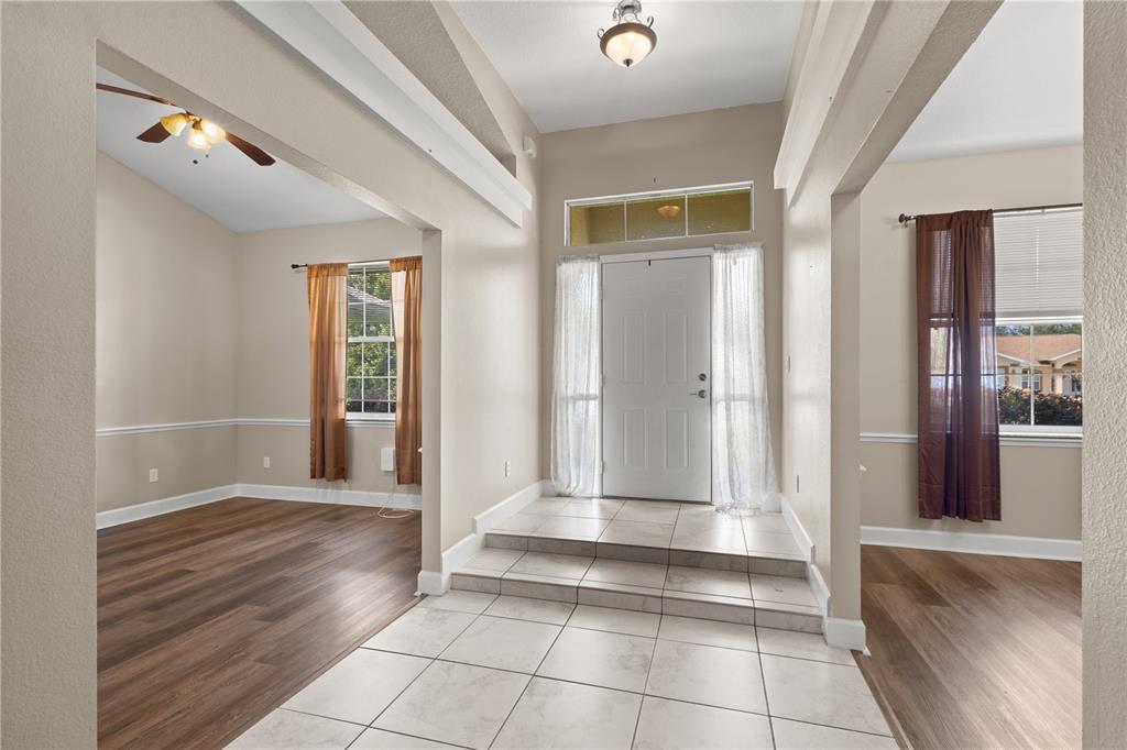 An entryway with tiled steps leading to a front door between two rooms with flooring — 5320 SW 115TH LOOP, OCALA, FL