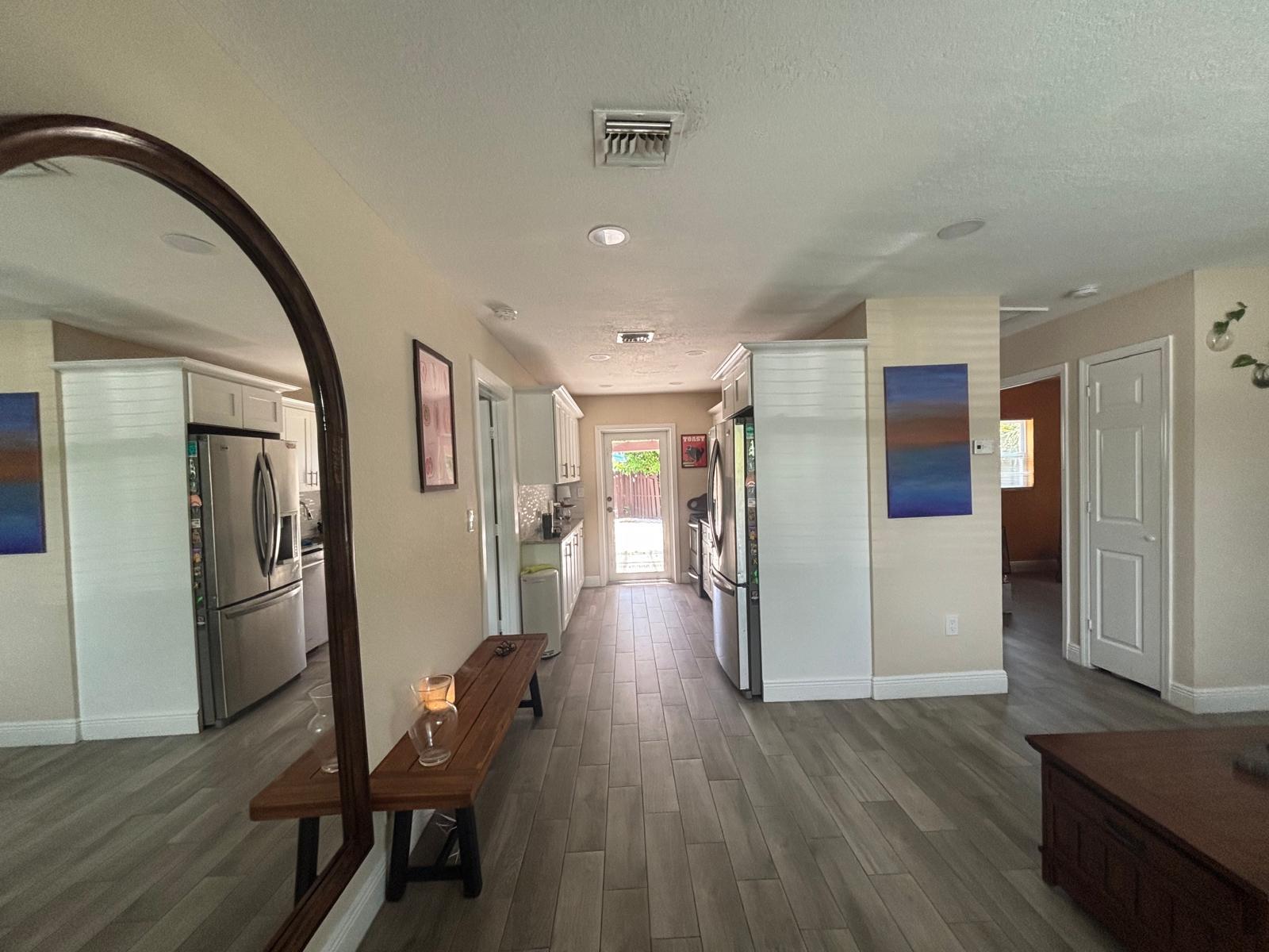 A hallway with wood-look tile flooring leads to a glass door opening to the outdoors — 2480 NE 13th Terrace, Pompano Beach FL 33064, POMPANO BEACH, FL