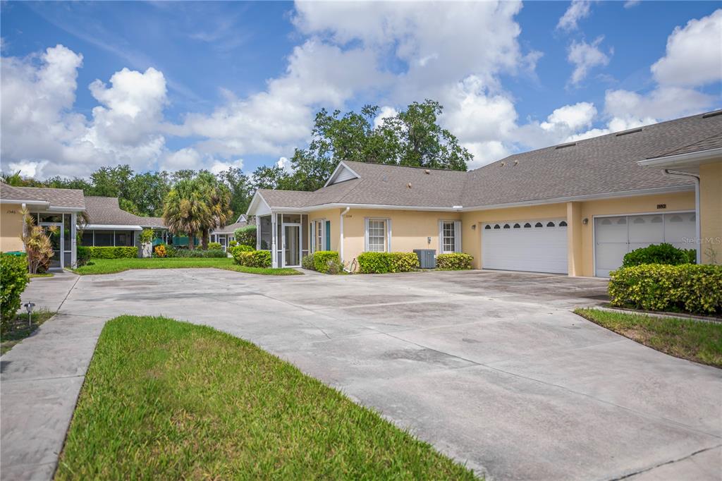 A view of a yellow single-story residential building with a concrete driveway and garage — 1554 RED OAK LANE, PORT CHARLOTTE, FL