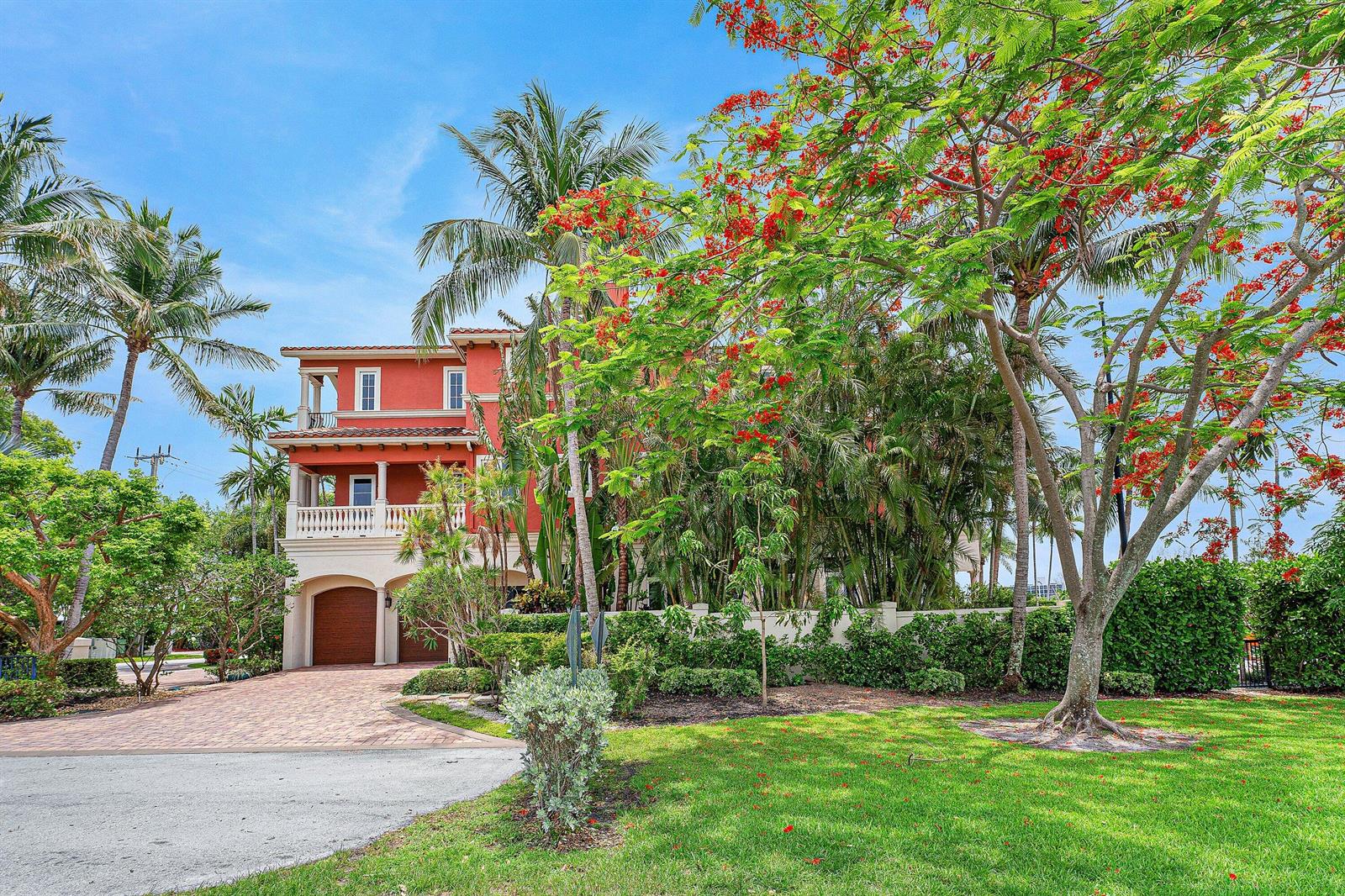 A three-story orange house with a paved driveway, palm trees, and a blooming tree — 453 NE 19th Avenue, Deerfield Beach FL 33441, DEERFIELD BEACH, FL