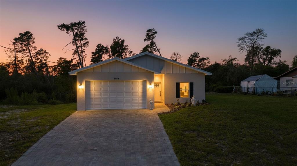 A single-story house with a white exterior, a paved driveway, and a two-car garage — 6454 FREEPORT DRIVE, SPRING HILL, FL