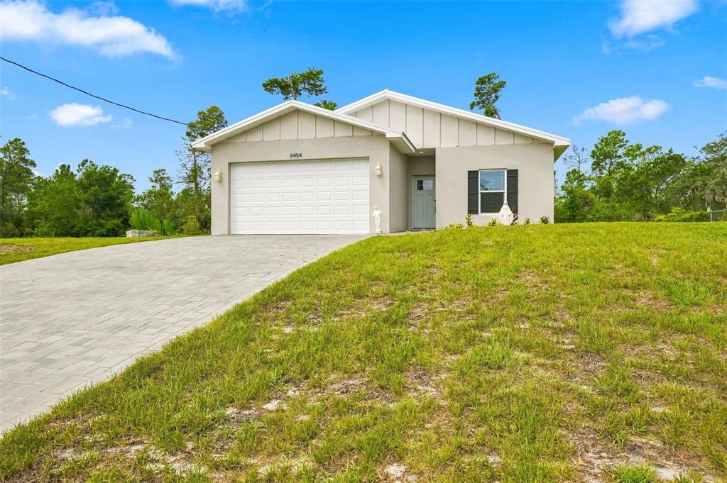 A single-story house with a beige exterior, a two-car garage, and a paved driveway — 6454 FREEPORT DRIVE, SPRING HILL, FL