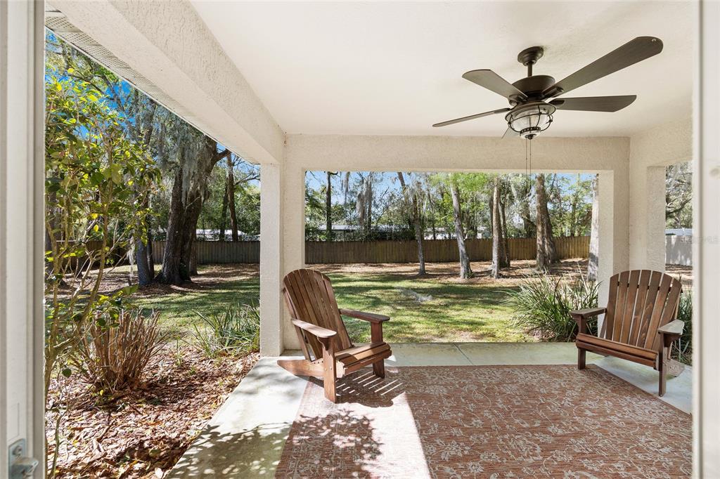 A covered patio features a ceiling fan, a patterned rug, and two wooden chairs — 4515 NW 6TH CIRCLE, OCALA, FL
