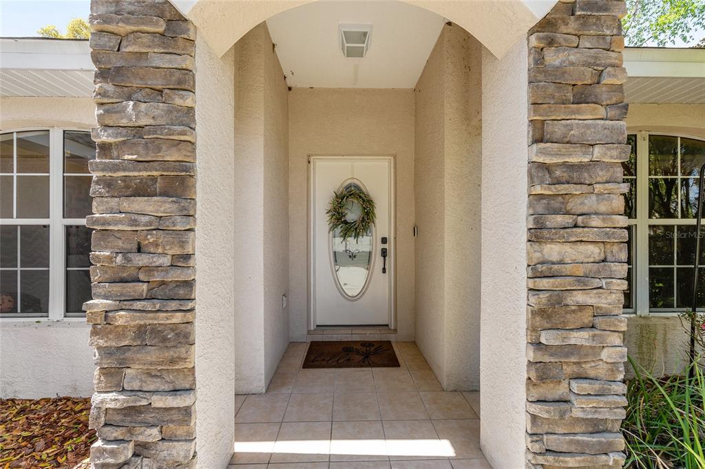 A covered entryway features a white front door with an oval window and stone pillars — 4515 NW 6TH CIRCLE, OCALA, FL