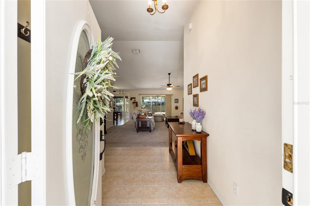 An entryway with tile flooring leads into a carpeted living room with a vaulted ceiling — 4515 NW 6TH CIRCLE, OCALA, FL