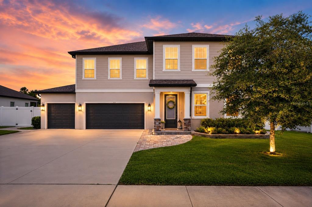 A two-story suburban house with a three-car garage and a paved walkway at sunset — 1112 PEARL TREE ROAD, DELTONA, FL