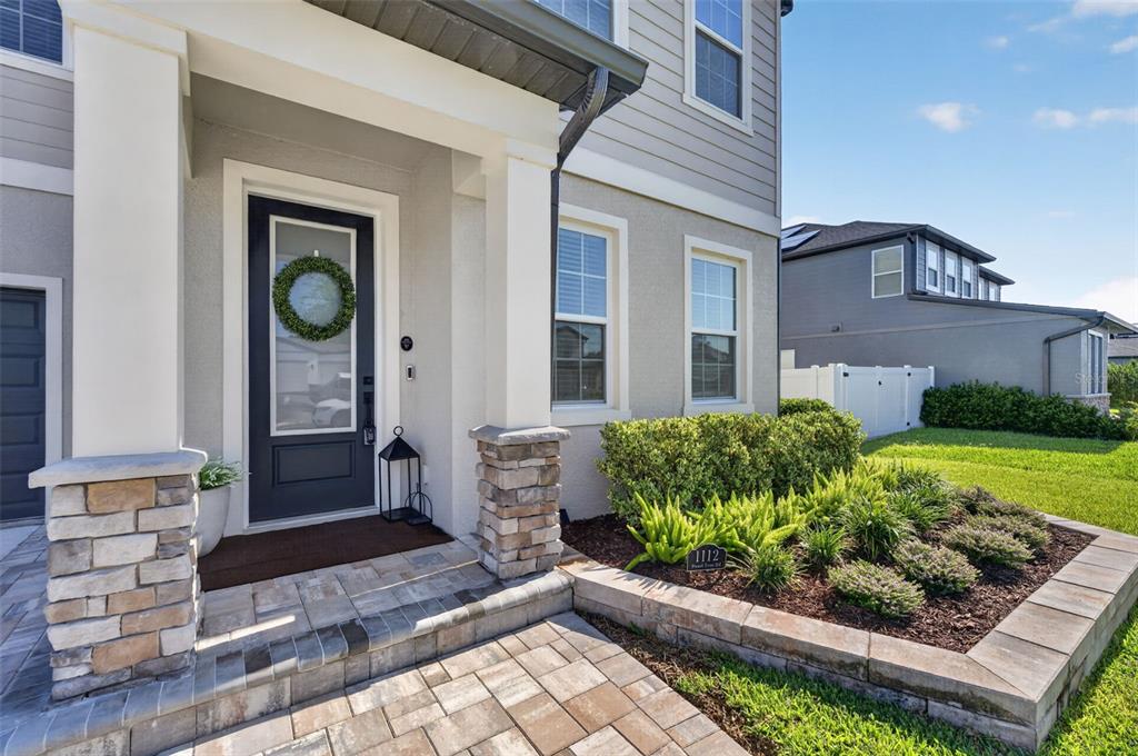 The exterior of a two-story house features a stone-accented porch, a dark front door, and landscaping — 1112 PEARL TREE ROAD, DELTONA, FL