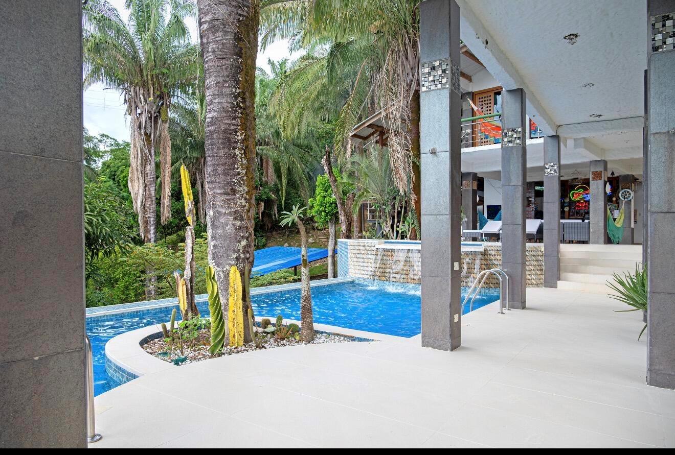 A swimming pool with a waterfall feature sits on a patio next to a building — El Paraiso Del Lago, FL