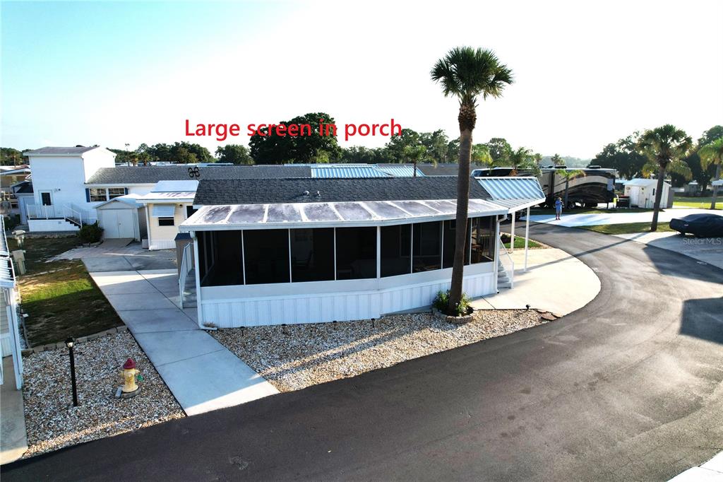 An aerial view of a mobile home featuring a large screened-in porch and a palm tree — 42769 HIGHWAY 27 UNIT 174, DAVENPORT, FL