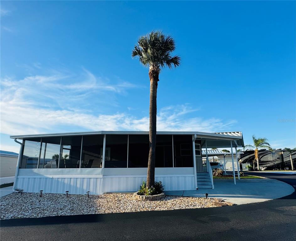 A mobile home with a screened-in porch and a tall palm tree in front — 42769 HIGHWAY 27 UNIT 174, DAVENPORT, FL