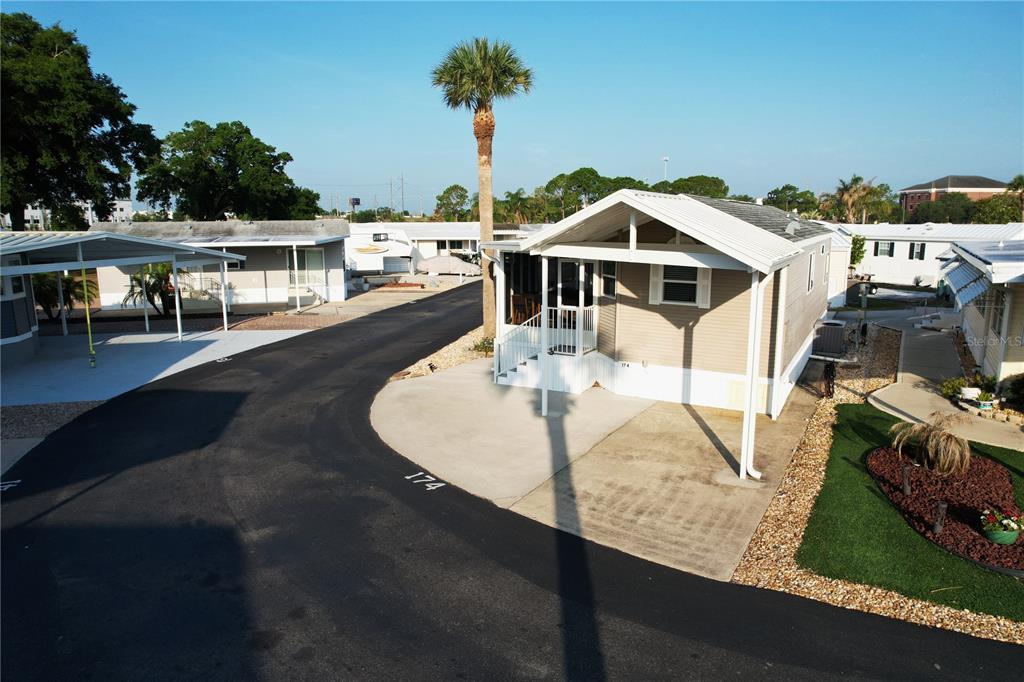 An exterior view of a tan mobile home with a carport and a palm tree — 42769 HIGHWAY 27 UNIT 174, DAVENPORT, FL