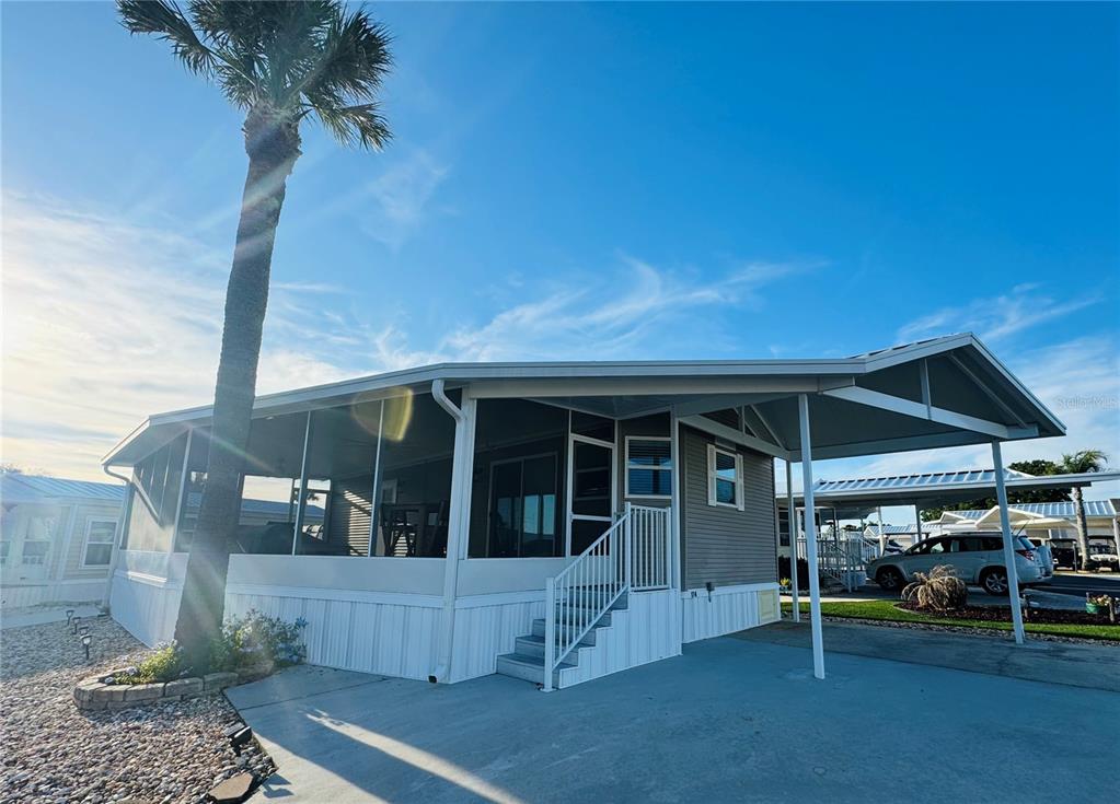 A manufactured home with a screened-in porch, a carport, and a palm tree in front — 42769 HIGHWAY 27 UNIT 174, DAVENPORT, FL