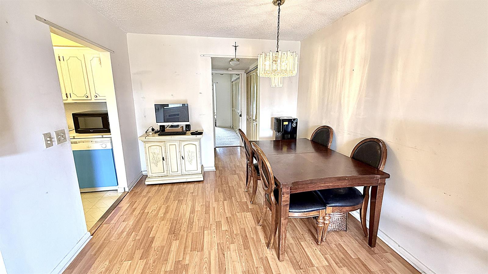 A dining area features a wooden table, chairs, a chandelier, and a computer console — 122 Oakridge I, Deerfield Beach FL 33442, DEERFIELD BEACH, FL