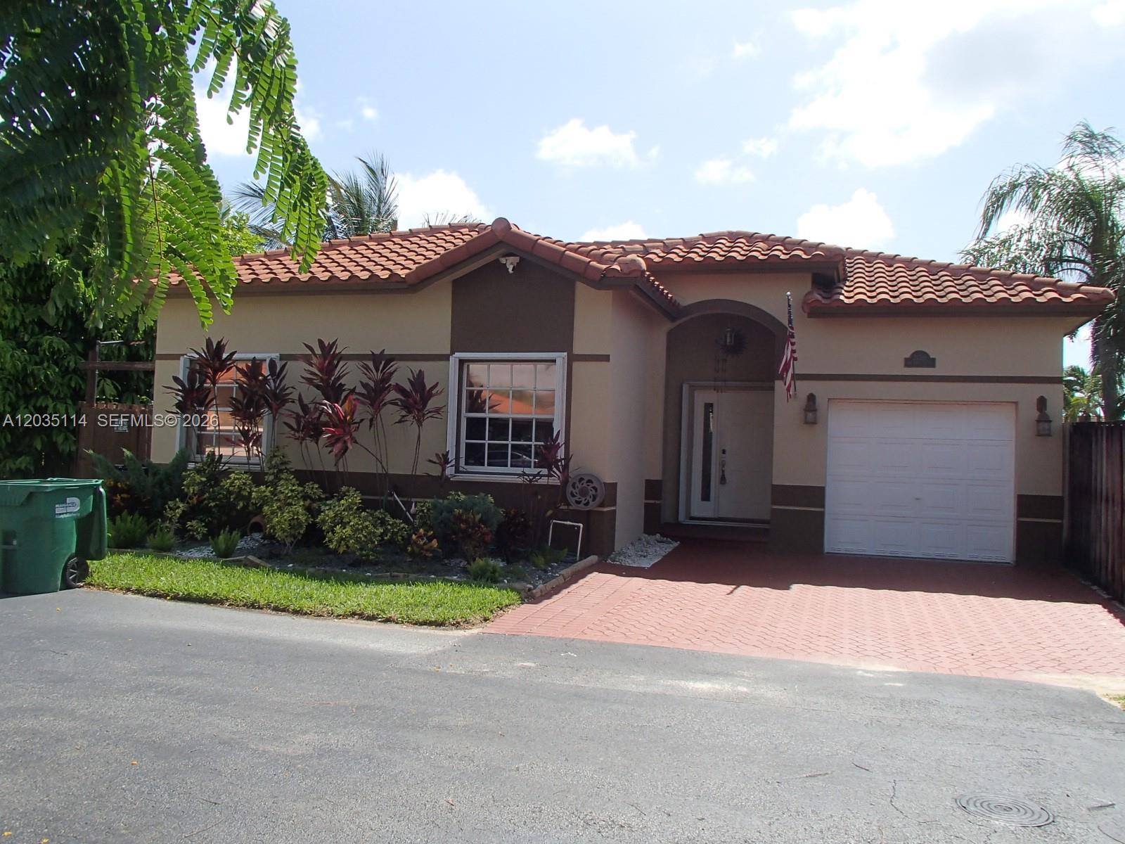 A single-story house with a tiled roof, a paved driveway, and a small front garden — CUTLER BAY, FL