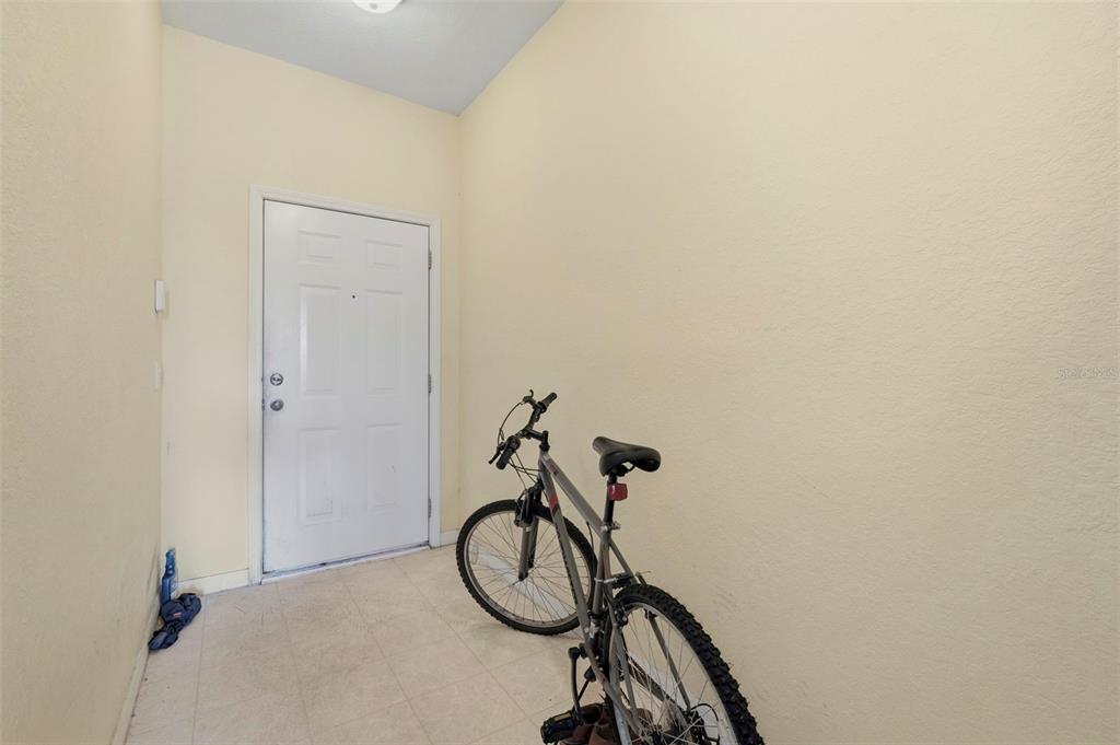 A bicycle sits in a small, tiled entryway with cream-colored walls and a white door — 11082 WINTER CREST DRIVE, RIVERVIEW, FL