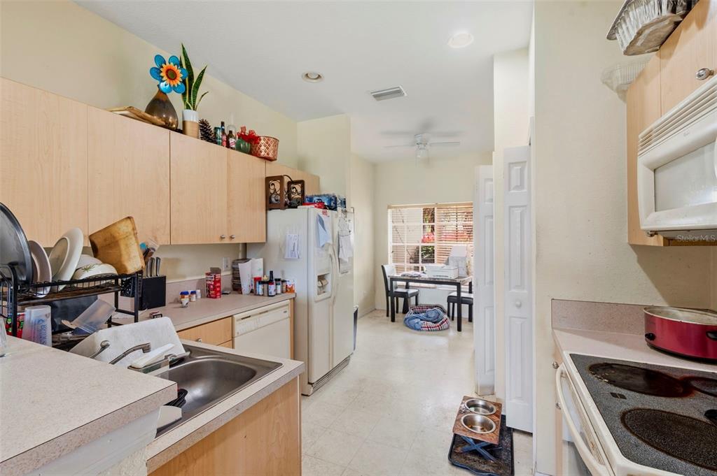 A kitchen with light wood cabinets, white appliances, and a small dining area in the back — 11082 WINTER CREST DRIVE, RIVERVIEW, FL