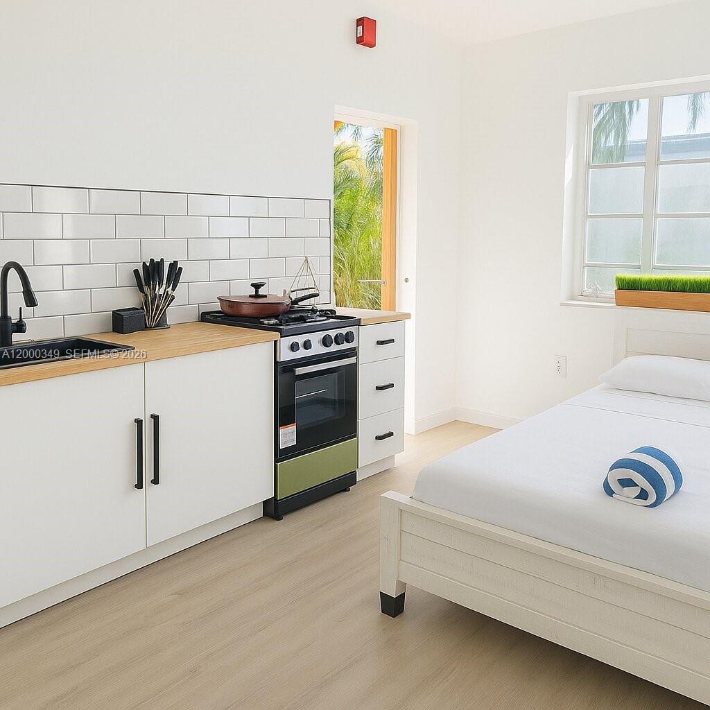 A studio apartment features a kitchenette with white cabinets, a gas stove, and a bed — 301 86th St # 4A, Miami Beach FL 33141, MIAMI BEACH, FL