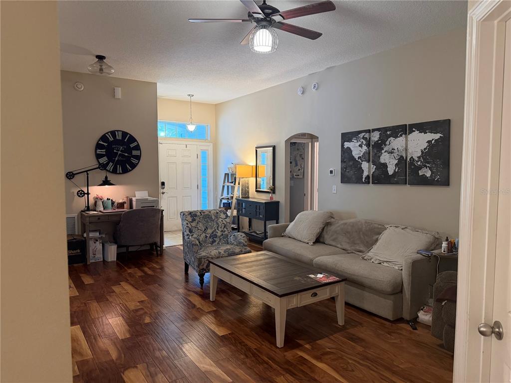 A living room features wood flooring, a beige sofa, a coffee table, and a desk area — 4851 NW 81ST AVENUE, GAINESVILLE, FL