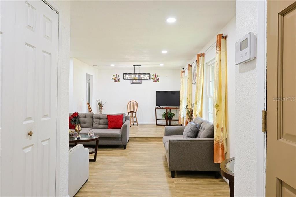 A living room features light wood-look flooring, two gray sofas, and a television on a stand — 2244 MENOMONEE COURT, ORLANDO, FL