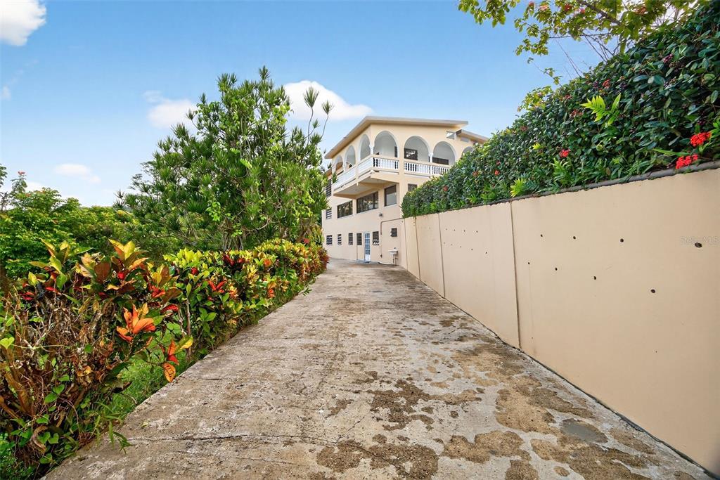 A concrete driveway leads toward a multi-story house with arched balconies and a retaining wall — PR-184 KM 32.4 S BEATRIZ, CAYEY, PR