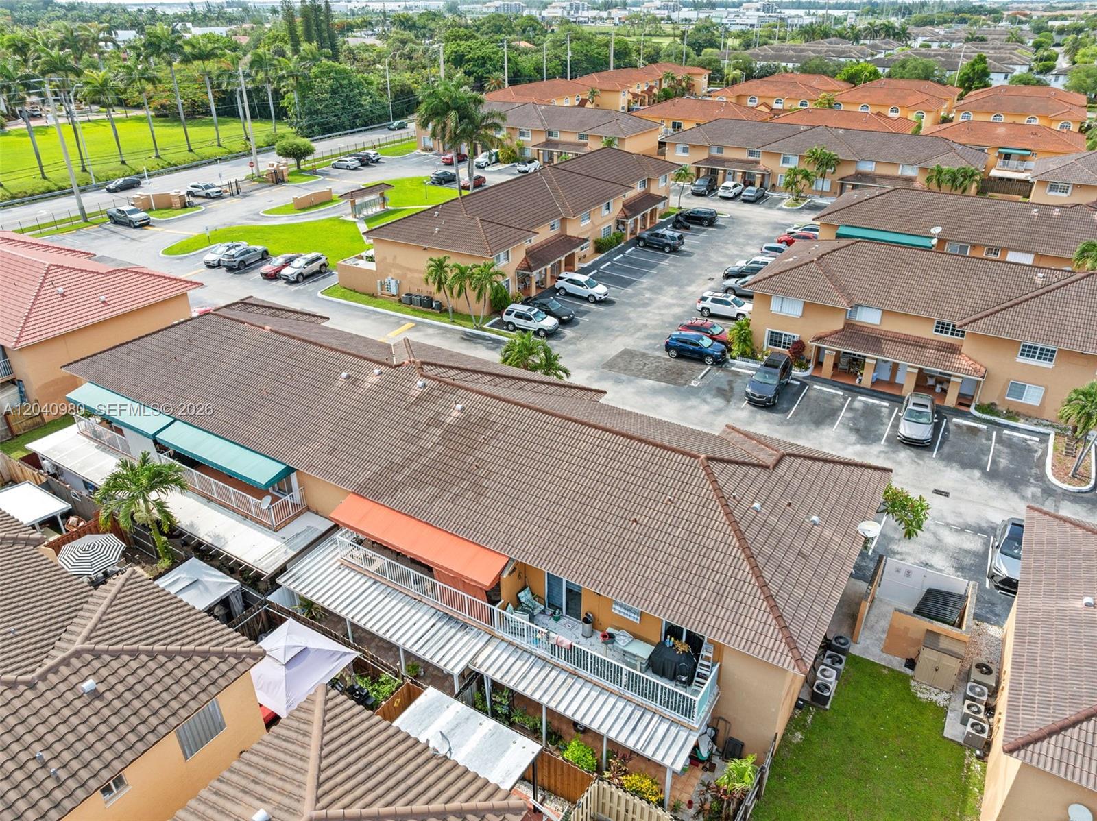 An aerial view shows multiple tan townhouses with brown tile roofs and parking lots — 7817 W 36th Ave # 101, Hialeah FL 33018, HIALEAH, FL