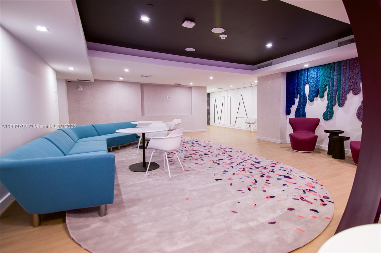 A modern lounge area features a blue sectional sofa, white tables, and a colorful rug — 227 NE 2nd St # 1707, Miami FL 33132, MIAMI, FL