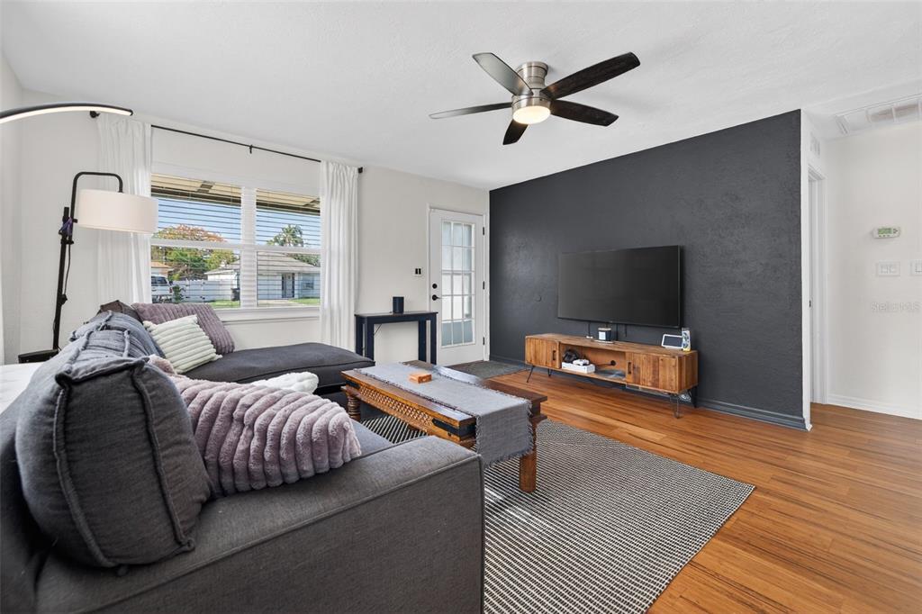 A living room features a dark accent wall, a sectional sofa, and wood-look flooring — 3766 56TH AVENUE N, ST PETERSBURG, FL