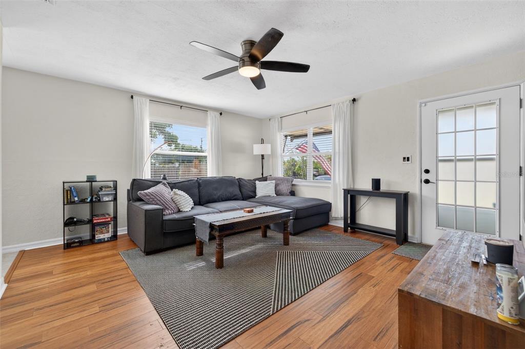 A living room features a gray sectional sofa, a coffee table, and wood-look flooring — 3766 56TH AVENUE N, ST PETERSBURG, FL
