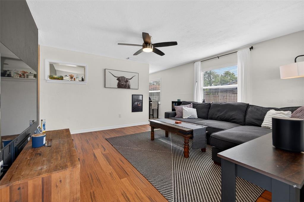 A living room features a dark sectional sofa, a geometric rug, and wood flooring — 3766 56TH AVENUE N, ST PETERSBURG, FL