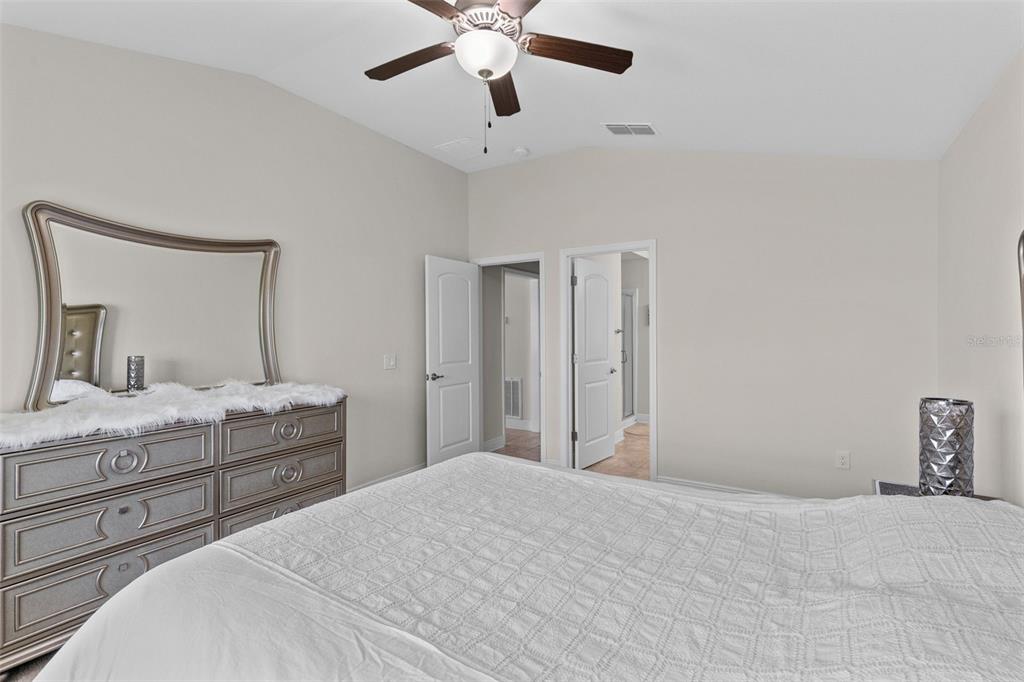 A bedroom features a dresser with a mirror, a bed, and two open doorways — 399 BUCHANNAN DRIVE, DAVENPORT, FL