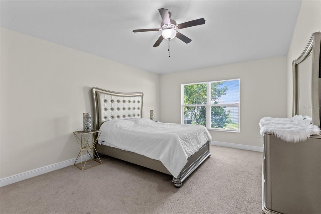 A bedroom features a tufted headboard, a ceiling fan, and a dresser with a mirror — 399 BUCHANNAN DRIVE, DAVENPORT, FL