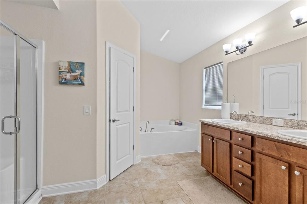 A bathroom features a double vanity, a soaking tub, a glass shower, and tile flooring — 399 BUCHANNAN DRIVE, DAVENPORT, FL