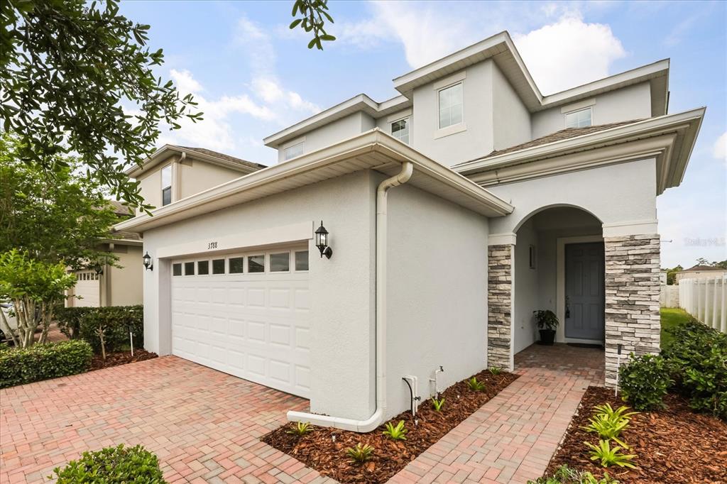 A two-story house with a brick driveway, a two-car garage, and a stone-accented entryway — 3788 SALTMARSH LOOP, SANFORD, FL