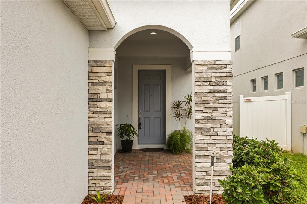 A front entryway features a blue door, stone pillars, and a brick paver walkway — 3788 SALTMARSH LOOP, SANFORD, FL