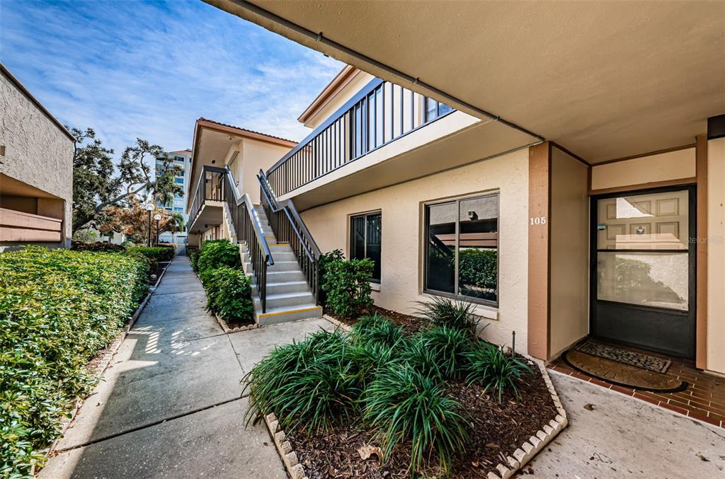 An exterior view of a two-story apartment building with a concrete staircase and unit 105 — 6269 PALMA DEL MAR BOULEVARD S UNIT 105, ST PETERSBURG, FL