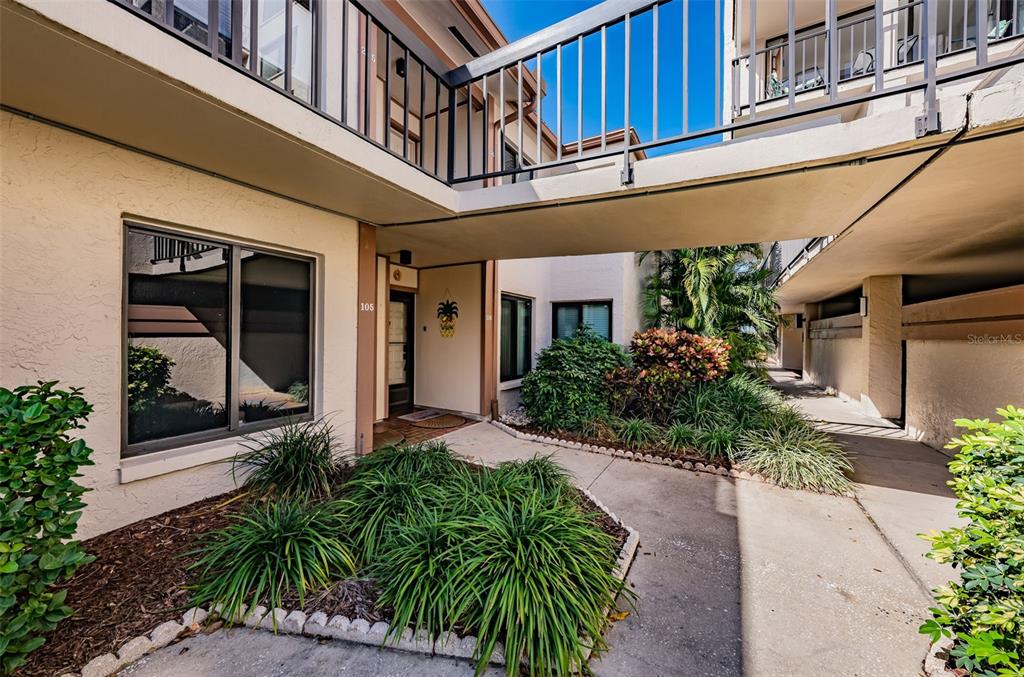 An exterior view of a multi-story apartment building with a walkway connecting two sections — 6269 PALMA DEL MAR BOULEVARD S UNIT 105, ST PETERSBURG, FL