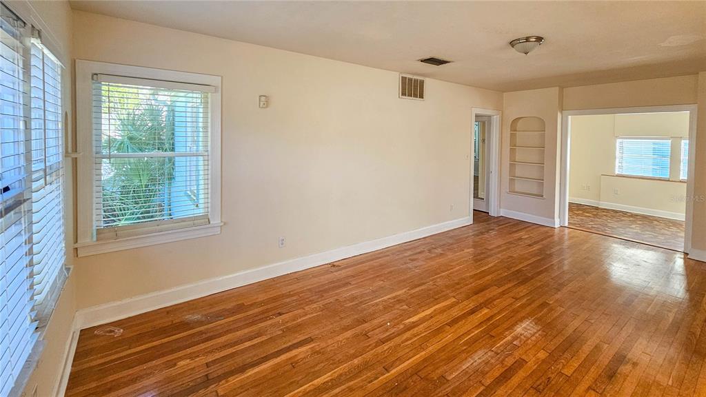 An empty living room with hardwood floors, white walls, and an arched built-in bookshelf — 860 16TH AVENUE S, ST PETERSBURG, FL
