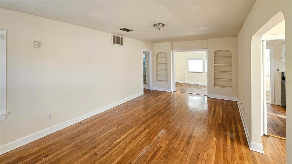 A living room with hardwood floors, built-in shelving, and an arched doorway leading to another room — 860 16TH AVENUE S, ST PETERSBURG, FL